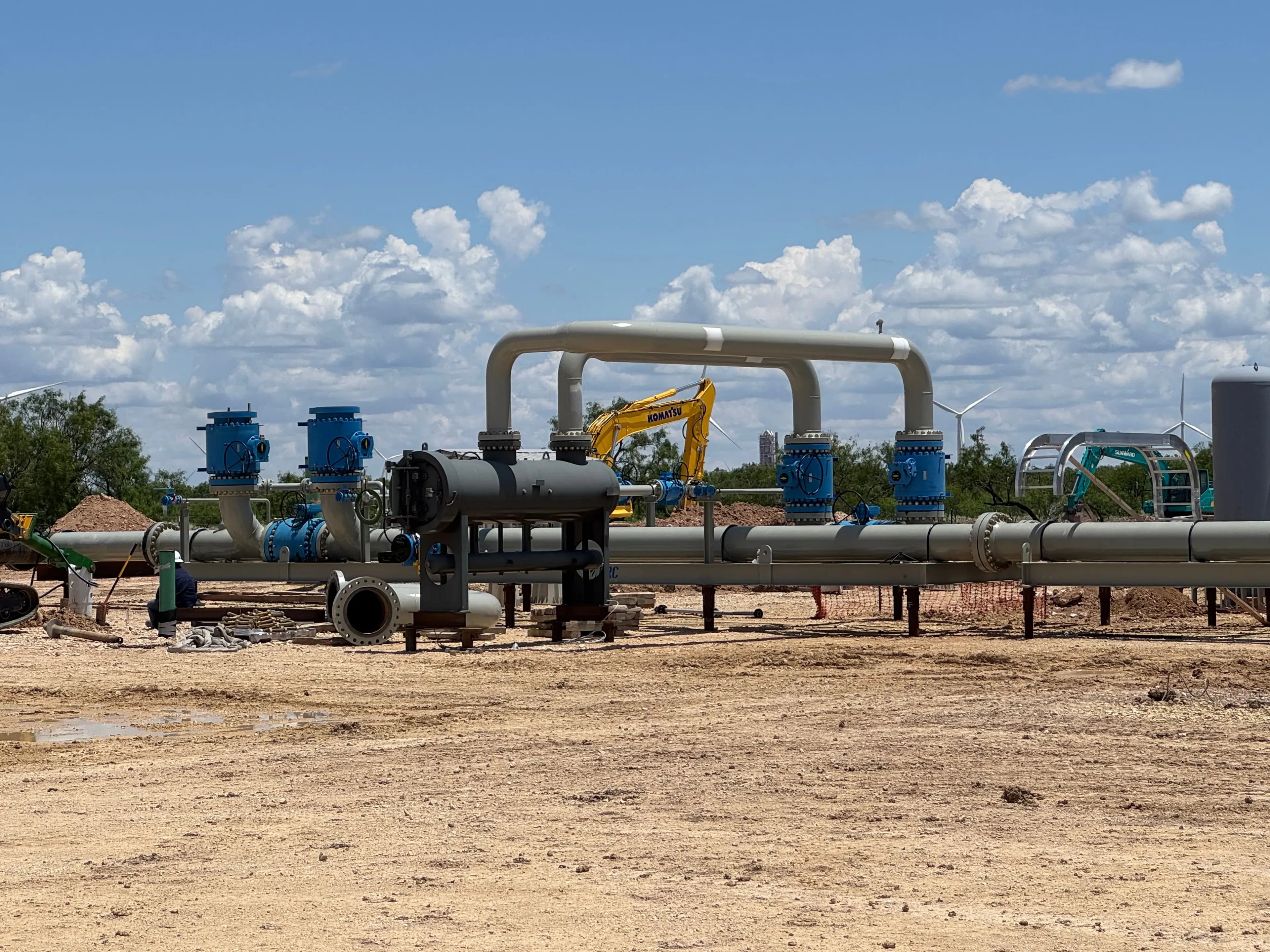 An above-ground pipeline run with valve assemblies and a pipe header loop at an outdoor installation